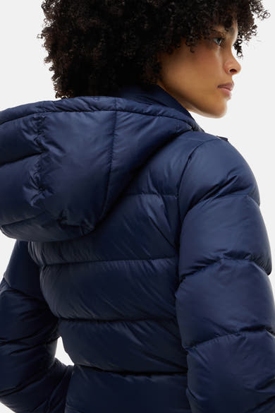 Navy blue quilted puffer jacket with hood, side view of model, shiny nylon material, structured stitching, cropped fit