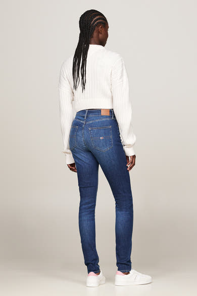 Jean skinny bleu foncé de Tommy Jeans, porté avec un pull en tricot côtelé, vue de dos.

