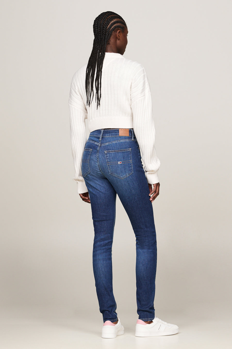 Jean skinny bleu foncé de Tommy Jeans, porté avec un pull en tricot côtelé, vue de dos.
