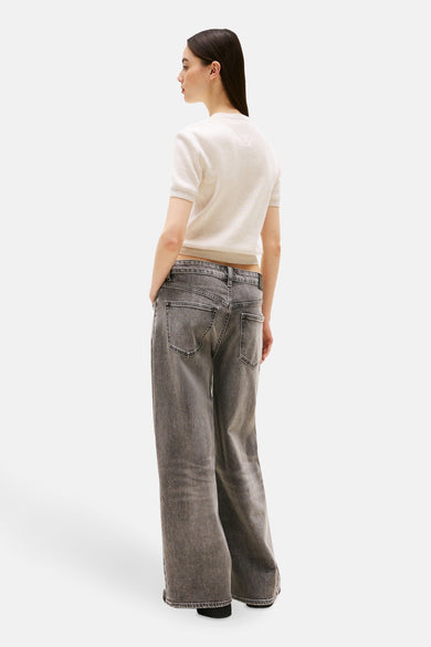 Pull à col rond beige de TOMMY JEANS, porté avec un jean gris à jambes larges.