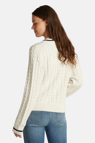 Pull à col en V blanc de TOMMY JEANS avec motif torsadé, porté avec un jean bleu.