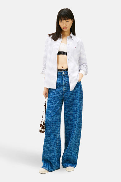 Blauw gestreept overhemd met lange mouwen van TOMMY JEANS, open gedragen over een witte top, met een bedrukte jeans.
