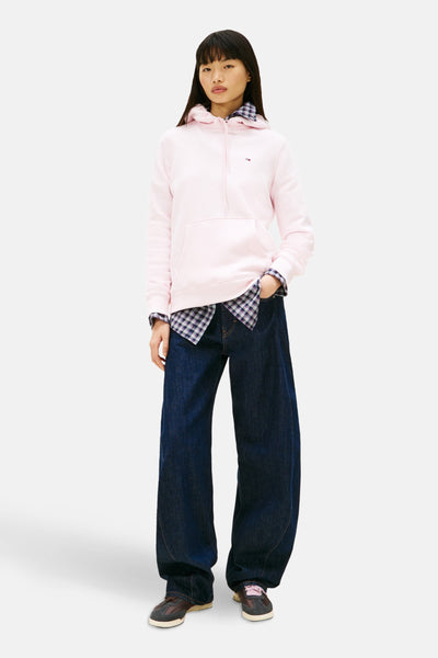 Sweatshirt van TOMMY JEANS, gedragen over een geruit overhemd en een wijde blauwe jeans.