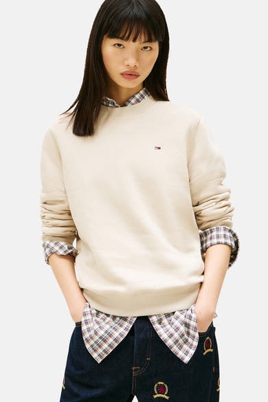 Beige ronde hals sweatshirt van TOMMY JEANS, gedragen over een geruit overhemd met een geborduurde jeans.