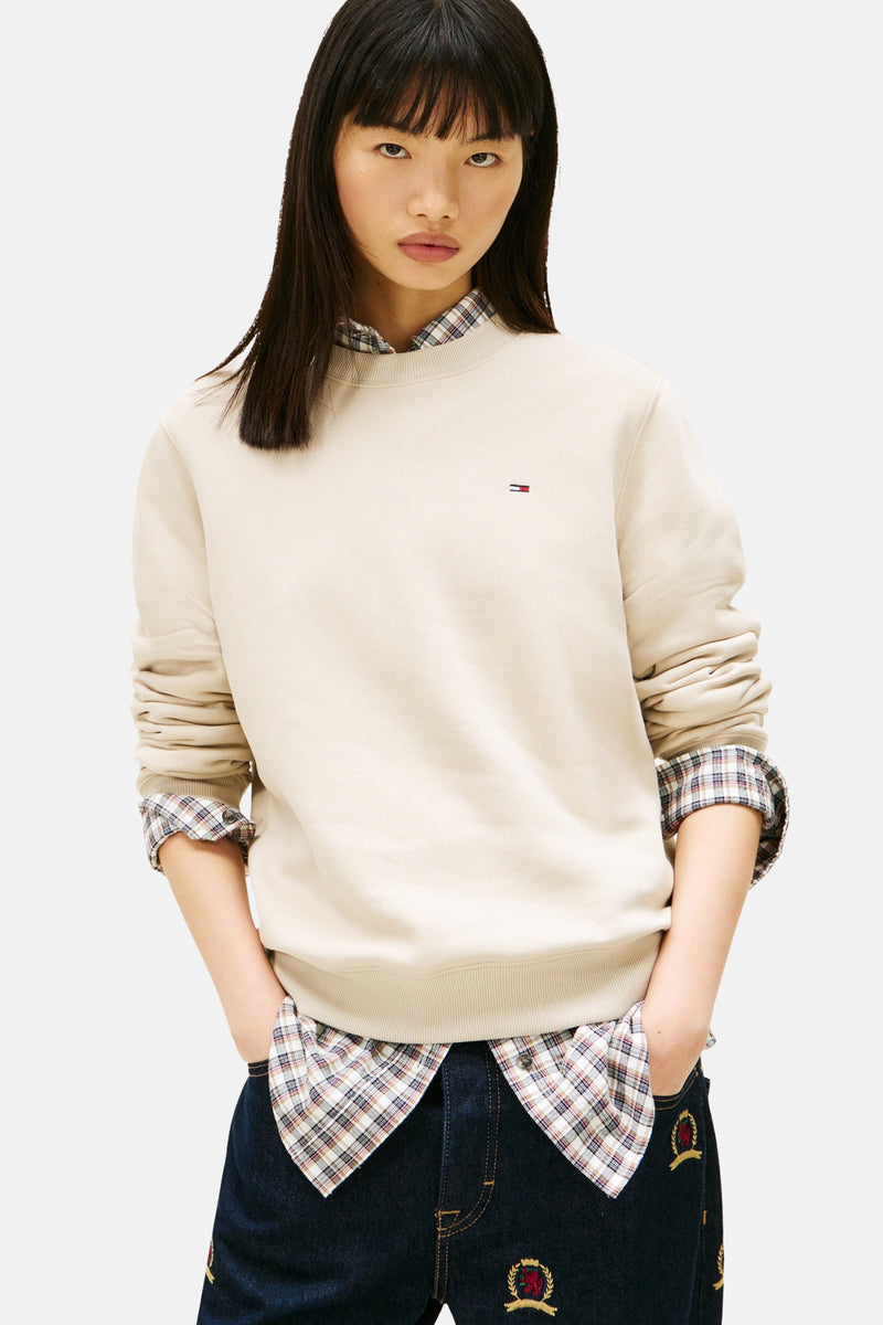 Beige ronde hals sweatshirt van TOMMY JEANS, gedragen over een geruit overhemd met een geborduurde jeans.