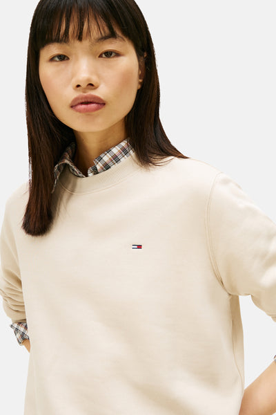 Beige sweatshirt van TOMMY JEANS, gedragen over een geruit overhemd, met een klein logo op de borst.