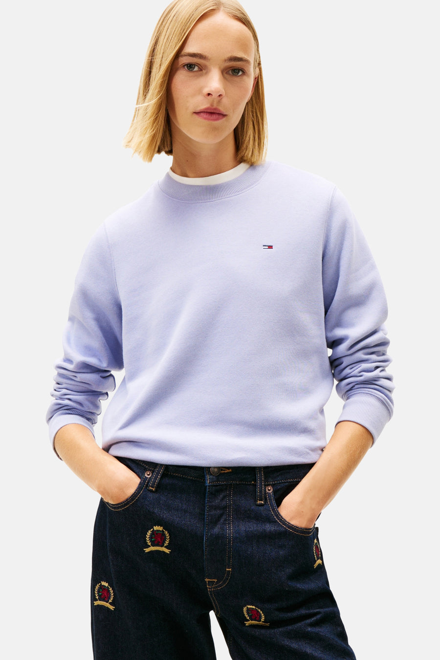 Paarse TOMMY JEANS sweater, achterkant, gedragen met een marineblauwe spijkerbroek met patroon.