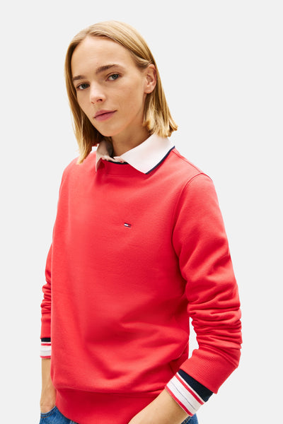 TOMMY JEANS rode rondehals sweatshirt, gedragen over een overhemd met witte kraag en gestreepte manchetten.