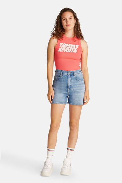 Korte spijkerbroek in lichtblauw van TOMMY JEANS, gedragen met een roze T-shirt met print en witte sneakers.