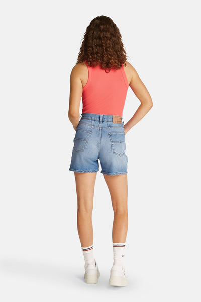 Lichtblauwe spijkerbroek van Tommy Jeans, gedragen met een roze tanktop en witte sokken.