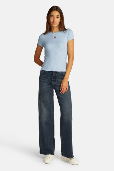 T-shirt bleu à manches courtes de Tommy Jeans, porté avec un jean ample et des baskets blanches.
