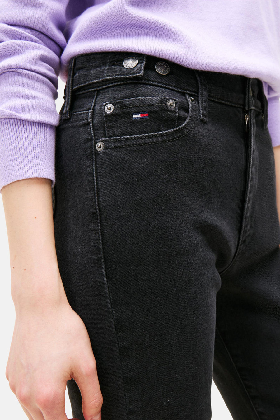 Wijde spijkerbroek in zwart denim van TOMMY JEANS, met zakdetails en metalen knopen, gedragen met een paarse trui.