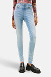 Jean skinny en denim bleu clair de TOMMY JEANS, porté avec un haut imprimé multicolore et des mocassins noirs à plateforme.