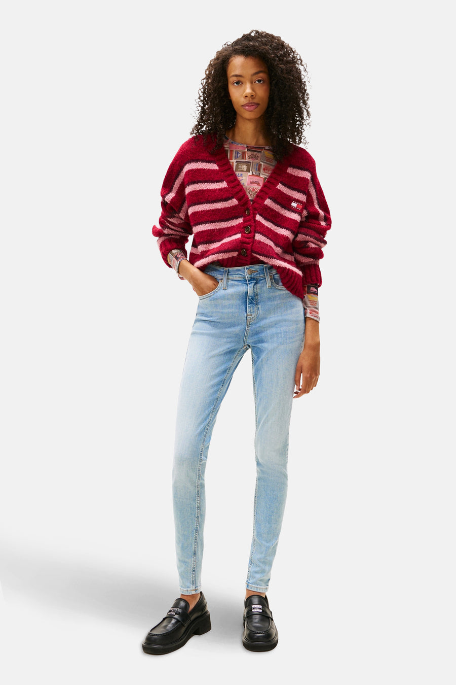 Jean skinny bleu clair en denim de TOMMY JEANS, porté avec un cardigan rayé rouge et des mocassins noirs.
