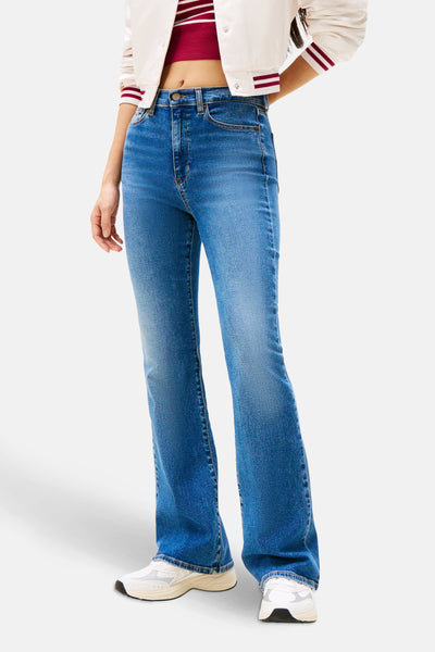Uitlopende jeans in middinblauw denim van TOMMY JEANS, met een flatterende pasvorm, gedragen met een gestreept topje en een jasje.