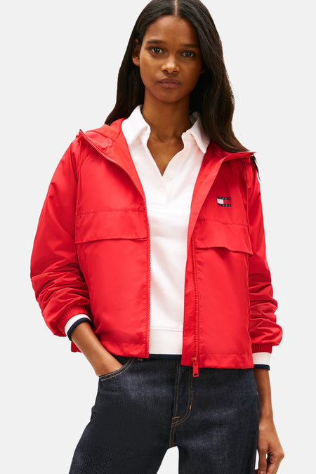 Veste courte rouge de TOMMY JEANS, portée avec une chemise blanche à col et un jean bleu foncé.
