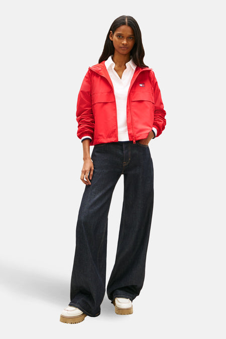 Veste courte rouge de TOMMY JEANS, portée sur un chemisier blanc et un jean large bleu foncé.