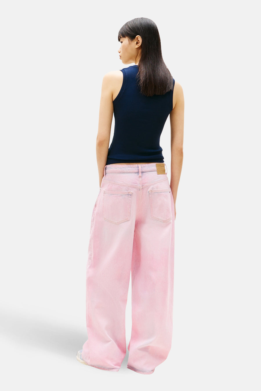 Top uni manches courtes bleu de Tommy Jeans, porté avec un pantalon rose ample, vue de dos.
