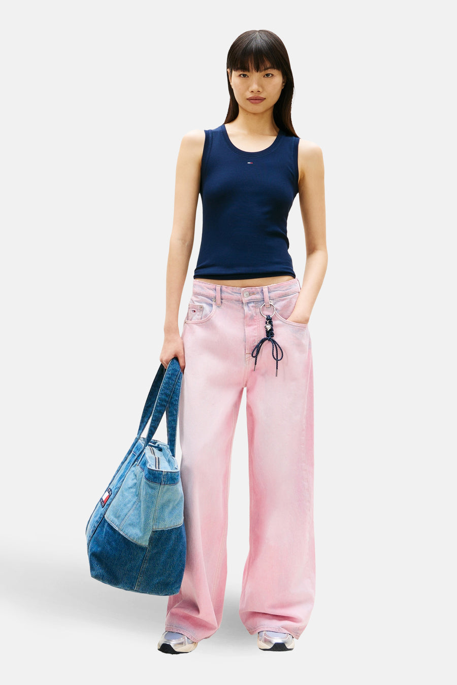 Top uni manches courtes bleu par Tommy Jeans, porté avec un pantalon rose délavé et un sac en jean.
