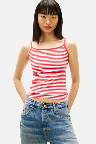 Multikleurig hemdje van TOMMY JEANS, met rode en witte strepen, gedragen met een wijde gescheurde spijkerbroek.