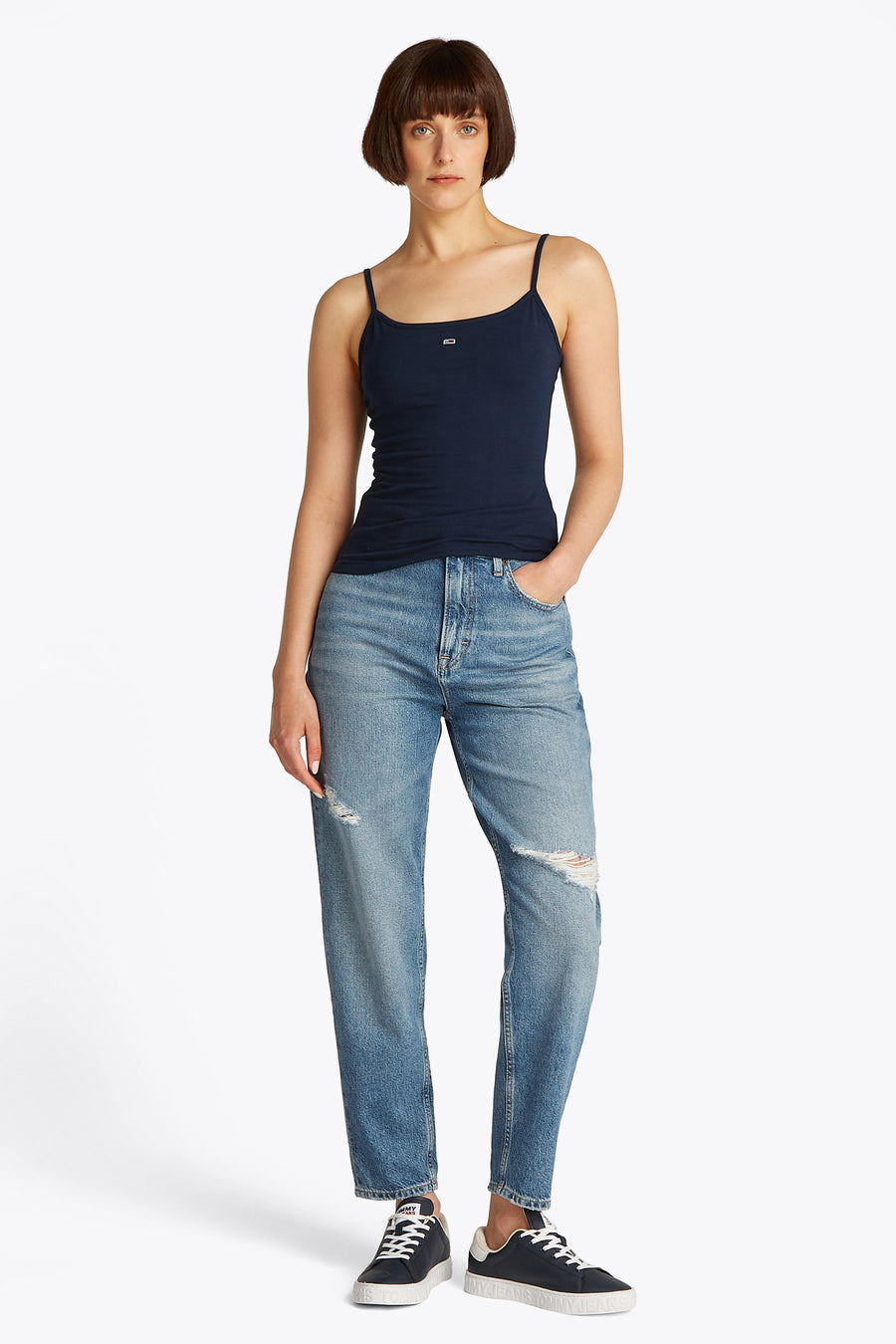 Débardeur bleu de TOMMY JEANS, porté avec un jean ample déchiré et des baskets.
