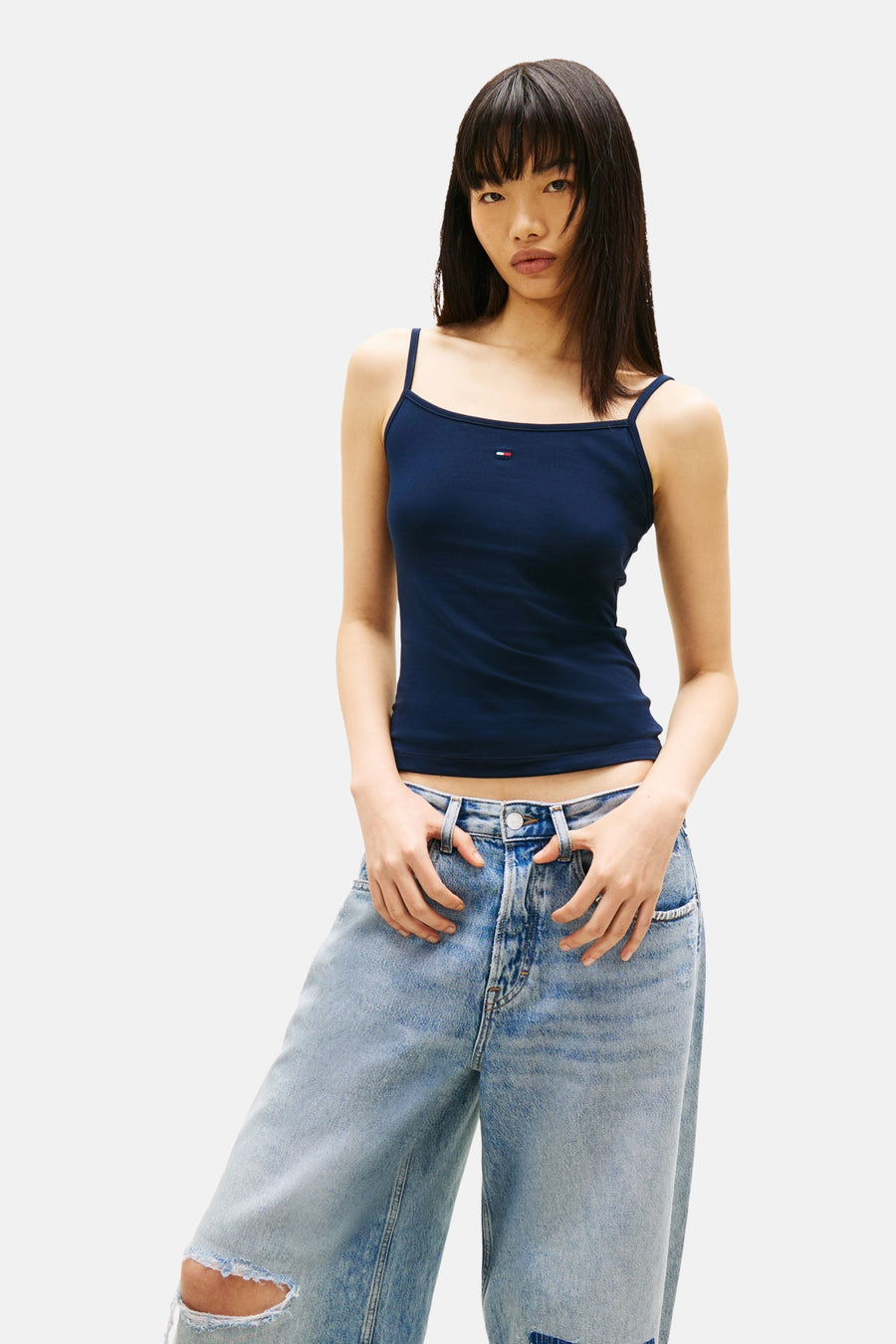Débardeur bleu marine par TOMMY JEANS, porté avec un jean ample délavé et troué.
