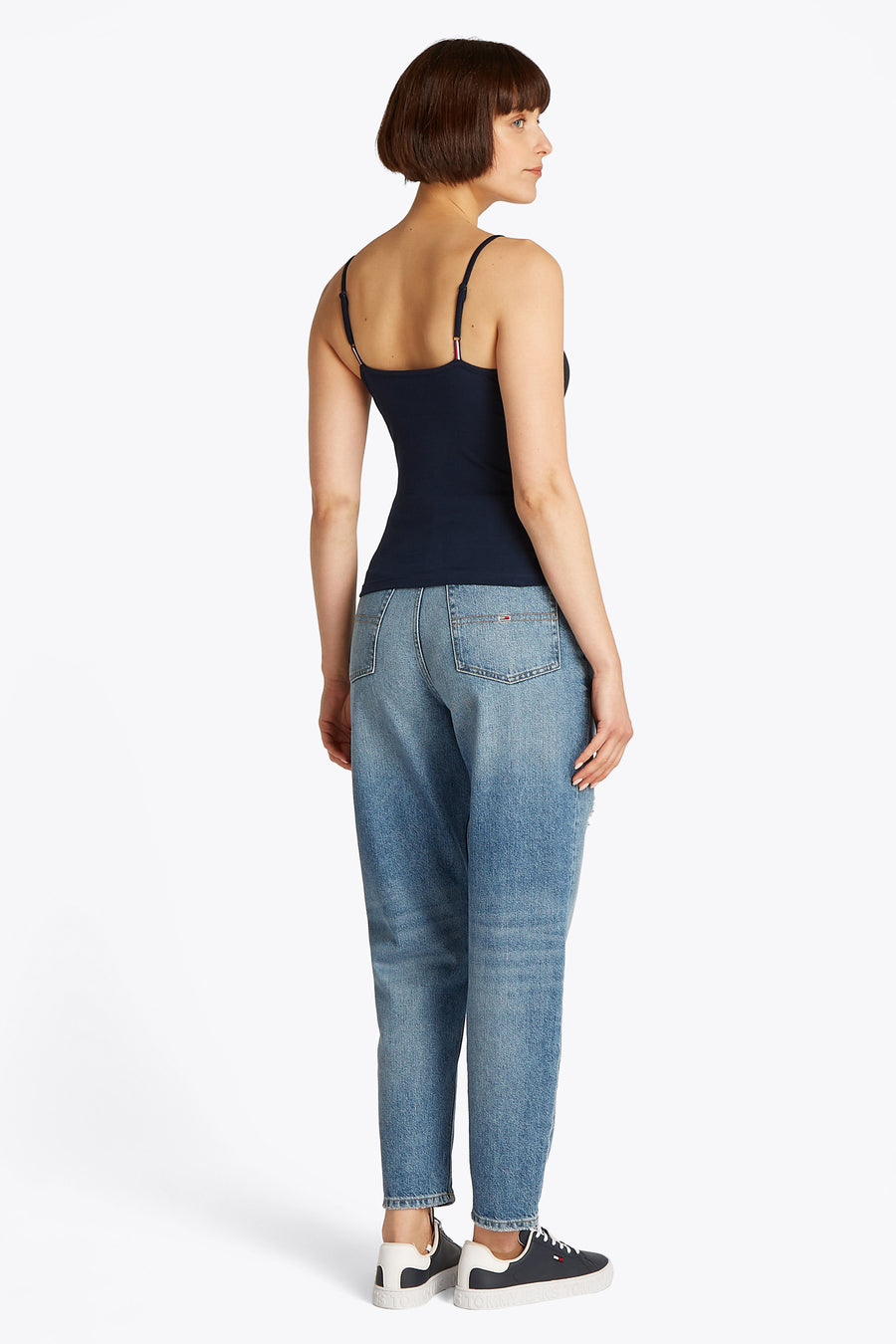 Débardeur bleu de TOMMY JEANS, porté avec un jean délavé et des baskets de sport blanches et bleu marine.