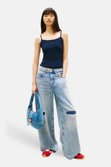 Débardeur bleu de TOMMY JEANS, porté avec un jean ample délavé et des chaussures rouges