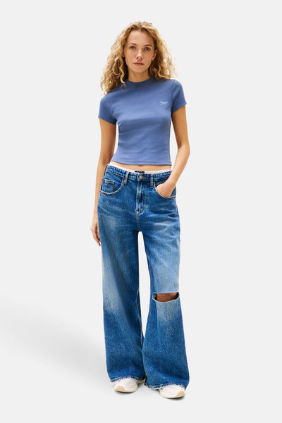 Blauwe T-shirt met korte mouwen van Tommy Jeans, gedragen met een wijde gescheurde jeans.