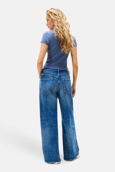 T-shirt bleu à manches courtes de TOMMY JEANS, porté avec un jean taille haute ample.