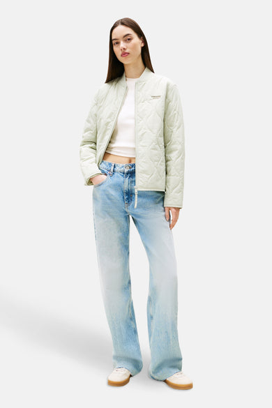 Korte groene jas van TOMMY JEANS met doorgestikt patroon, gedragen met een wijde jeans en een wit T-shirt.