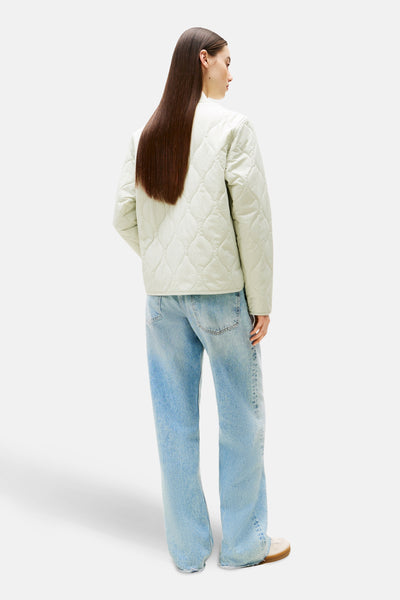 Kort poedergroen jasje van TOMMY JEANS, gewatteerd met ruitpatroon, gedragen met een wijde jeans.