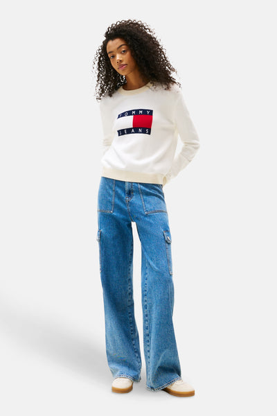 Ecru ronde hals trui van Tommy Jeans, met rechthoekig logo op de voorkant, gedragen met een blauwe cargobroek.