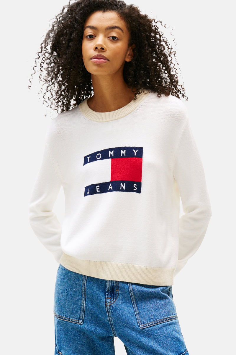 Ecru ronde hals trui van TOMMY JEANS, met iconisch vlaglogo op de voorkant, gedragen met een blauwe jeans.
