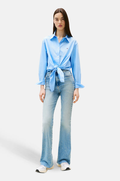 Blauw overhemd met lange mouwen van Tommy Jeans, geknoopt in de taille, gedragen met een wijde jeans en sneakers.