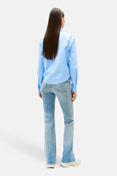 Lichtblauwe blouse met lange mouwen van Tommy Jeans, met een low-rise flared jeans en witte sneakers.