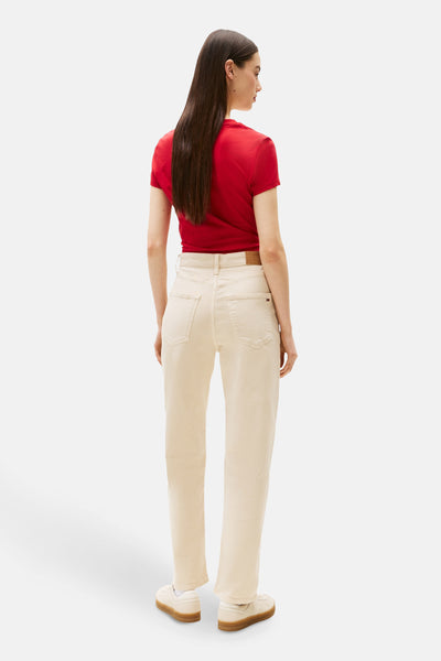 Beige kleurrijke broek van TOMMY JEANS, rechte pasvorm, gedragen met een rood T-shirt en witte schoenen.