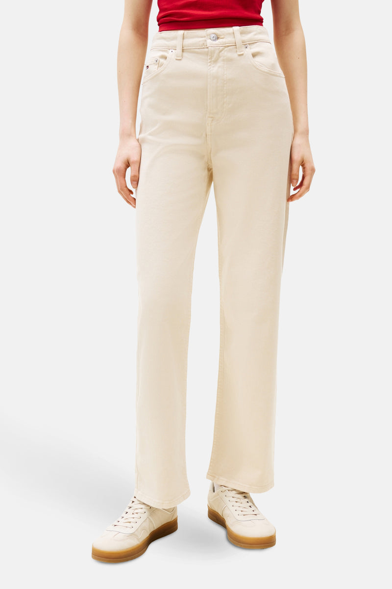 Beige kleurige broek van TOMMY JEANS, rechte pasvorm, gedragen met een rood T-shirt en witte sneakers.