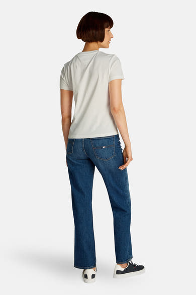 Top uni manches courtes blanc de Tommy Jeans, porté avec un jean bleu et des baskets noires et blanches.