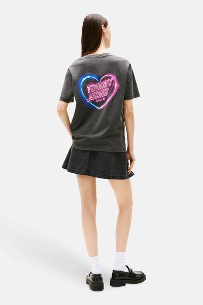 Grijze T-shirt met korte mouwen van TOMMY JEANS, blauw en roze hartprint op de rug, gedragen met een zwarte minirok.
