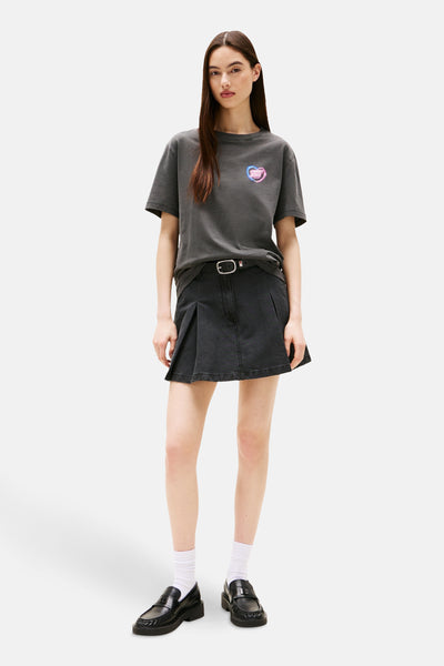 Grijze T-shirt met korte mouwen van TOMMY JEANS, met gestileerd hartlogo, gedragen met een zwarte rok en loafers.