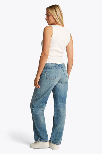 Ecru tanktop van TOMMY JEANS gedragen met een blauwe jeans en witte sneakers, achtergezicht.
