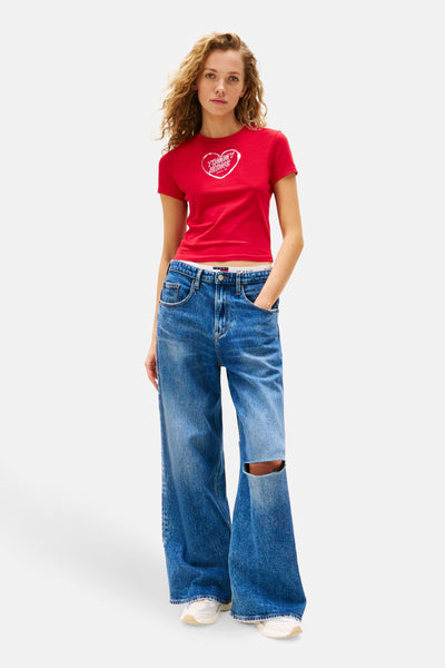 Rood T-shirt met korte mouwen van Tommy Jeans, gedragen met een low-rise spijkerbroek en sportschoenen.