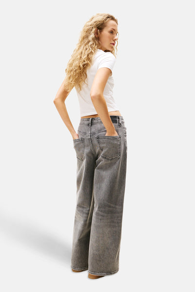 Wit T-shirt met korte mouwen van TOMMY JEANS, gedragen met een grijze wijde broek.