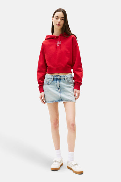 Rode hoodie van TOMMY JEANS, met decoratief hartlogo op de voorkant, gedragen met een spijker-minirok en sneakers.