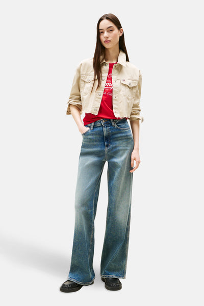 Korte beige jas van TOMMY JEANS, met rood T-shirt en wijde blauwe jeans.