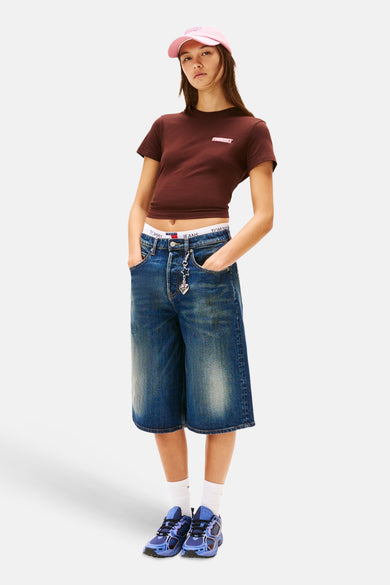 Bruin T-shirt met korte mouwen van Tommy Jeans, gedragen met een spijkerbroek en blauwe sneakers.
