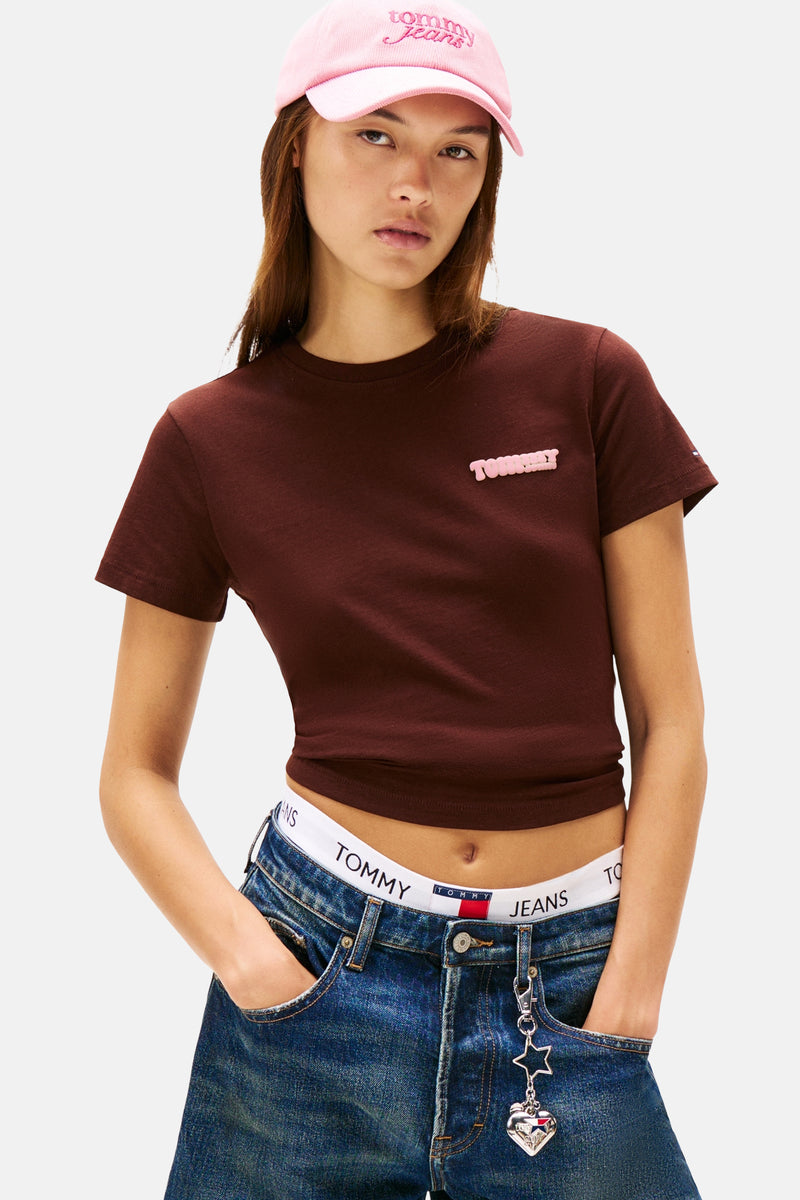Bruin T-shirt met korte mouwen van TOMMY JEANS met roze logo op de borst, gedragen met een low-rise jeans.