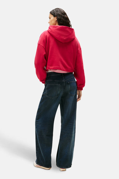 Roze hoodie van Tommy Jeans, gedragen met een wijde jeans en witte sneakers.