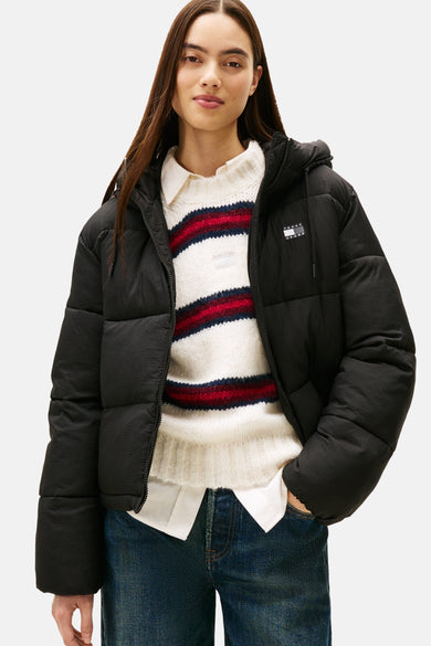 Veste courte noire de TOMMY JEANS, portée sur un pull rayé et un chemisier blanc, avec un jean.
